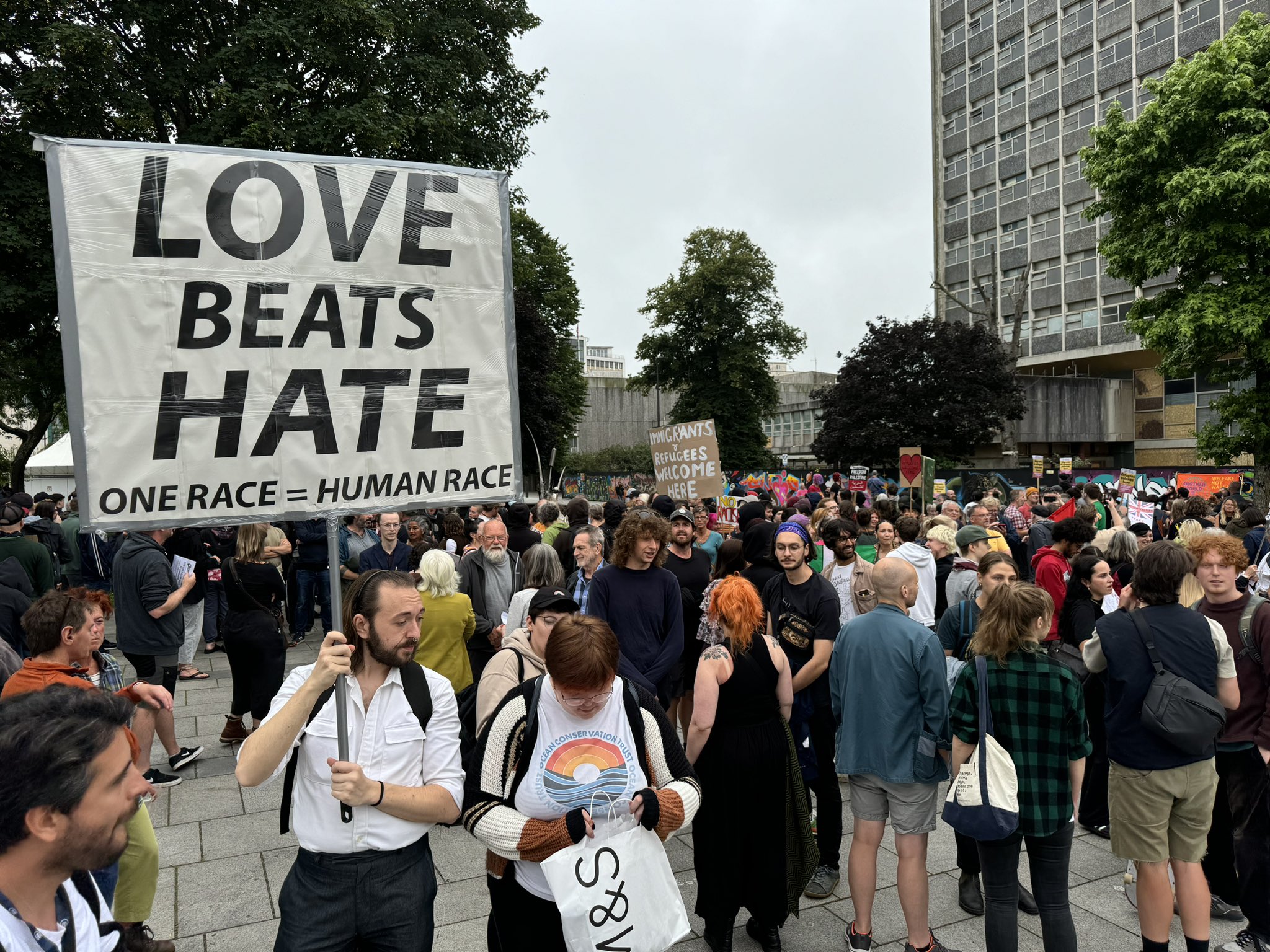 Protestors opposing fascist violence in Plymouth. The man at the front holds a sign which reads 'LOVE BEATS HATE. ONE RACE = HUMAN RACE'