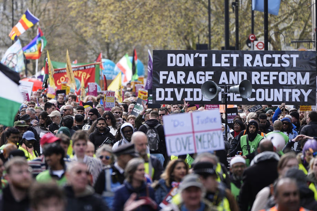 Picture showing a big crowd with a banner reading 'Don't let racist Farage and Reform divide the country'
